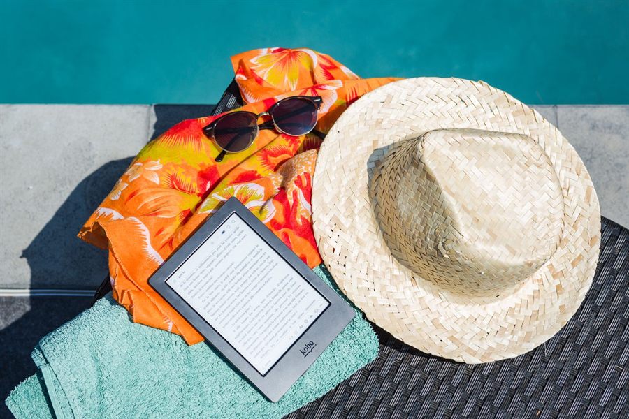 Sun hat, sunglasses and e-reader on a beach towel