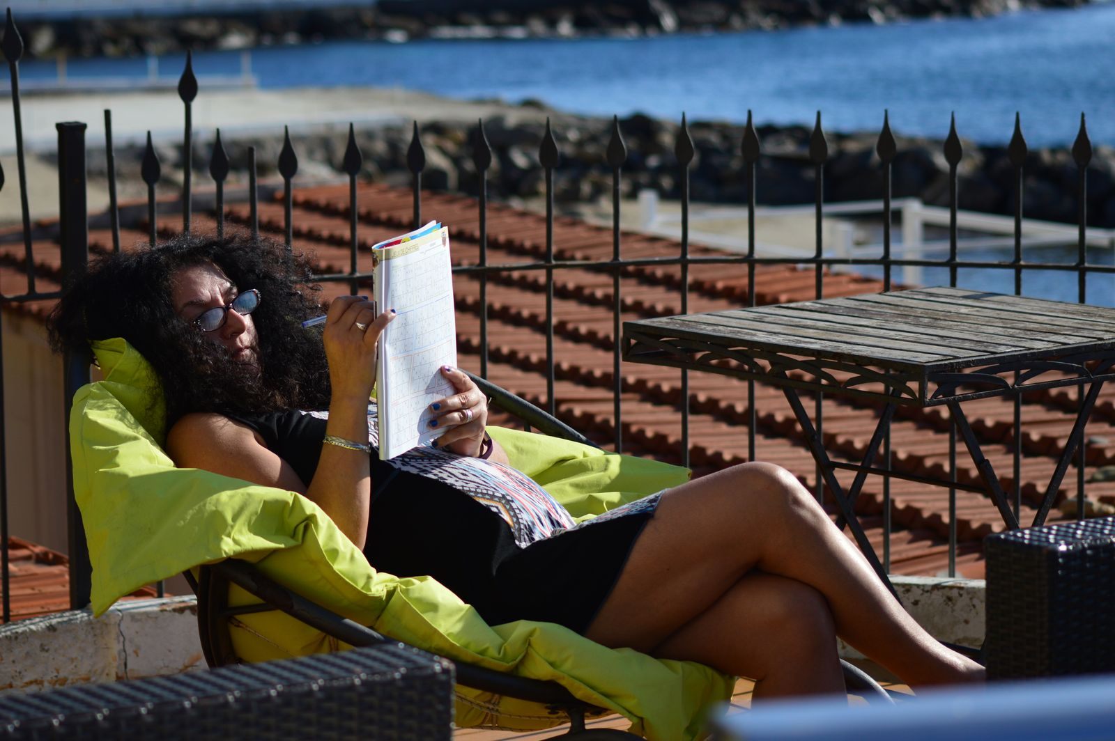Woman reading on a sunny terrace above the sea