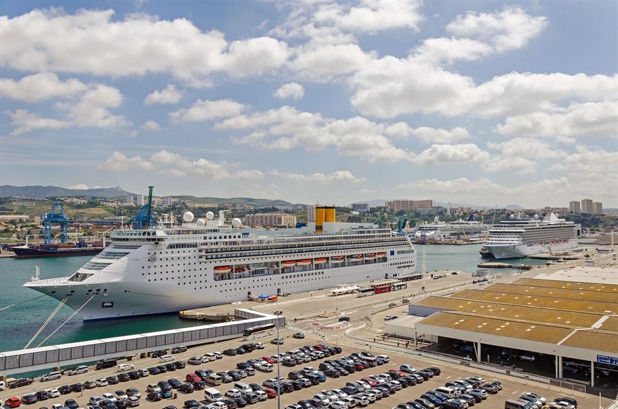 Cruise ship docked at a busy port beside a parking area